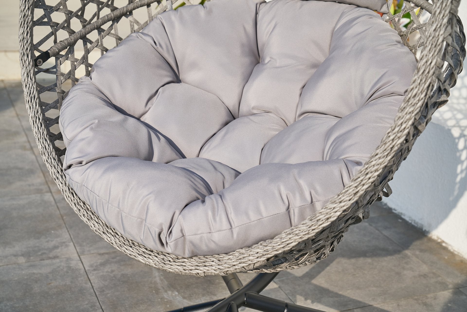Hängekorb Cookie mit hellgrauem Sitzkissen an einem grauen Outdoor-Aluminium‑Standfuß, auf Terrassenboden positioniert